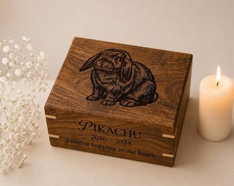 May include: A wooden box with a detailed engraving of a rabbit. The box is inscribed with the name "Pikachu" and dates 2016-2024, along with the phrase "Forever hopping in our hearts." A lit candle and white flowers are in the background.