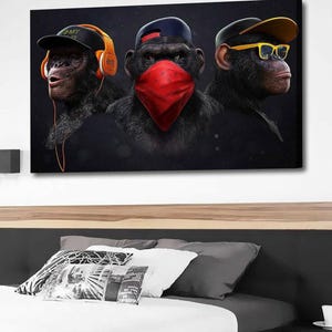 Könnte beinhalten: Leinwanddruck mit drei Affen, jeder mit einem anderen Accessoire. Einer trägt Kopfhörer und eine Kappe, ein anderer ein rotes Bandana und der dritte eine gelbe Brille und eine Kappe. Das Kunstwerk hängt über einem Bett.
