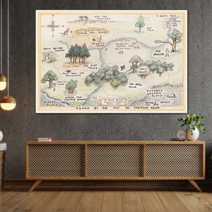 May include: A framed map illustration of a whimsical landscape with text labels like "Pooh Bears House" and "100 Acre Wood." The artwork features a compass rose and is in a vintage style with a cream-colored border.