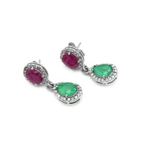 May include: A pair of silver earrings featuring a ruby and emerald gemstone design. Each earring has a round ruby at the top and a pear-shaped emerald below, both surrounded by a halo of small, clear gemstones.