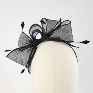 May include: Black mesh headband with a large bow and feather accents.