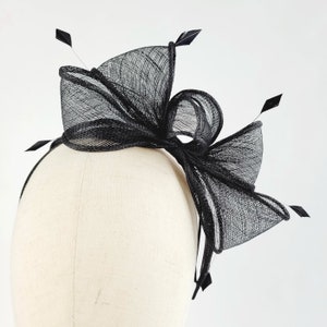 May include: Black mesh headband with a large bow and feathers.