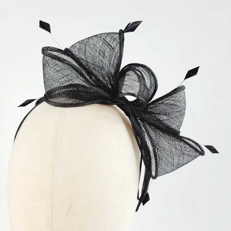 May include: Black mesh headband with a large bow and feathers.
