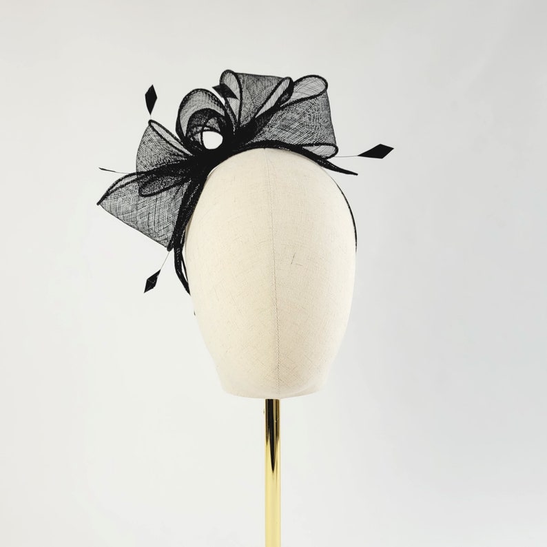 May include: Black mesh hair comb with a large bow. The comb is on a white mannequin head.