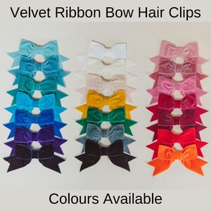 May include: A set of 16 velvet ribbon hair bows in various colors, including blue, green, purple, red, orange, and white. The bows are arranged in rows on a white background. "Colours Available" is written below the bows.
