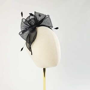 May include: A black mesh hair comb with a large bow. The comb is on a white mannequin head.