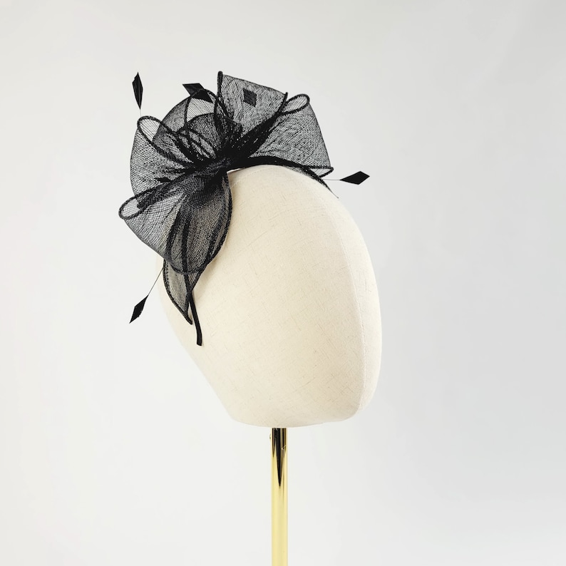 May include: A black mesh hair comb with a large bow. The comb is on a white mannequin head.