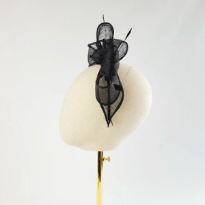 May include: A black feather hair comb with a delicate, intricate design. The comb is displayed on a white mannequin head.