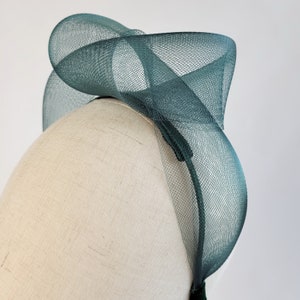 May include: A green mesh headband with a large, twisted bow. The headband is made of a soft, delicate material and is perfect for adding a touch of elegance to any outfit.