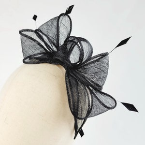 May include: Black mesh hair comb with a large bow and feathers. The comb is designed for a wedding or special occasion.