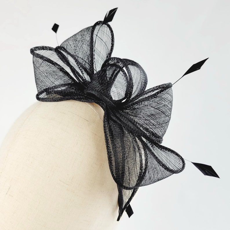 May include: Black mesh hair comb with a large bow and feathers. The comb is designed for a wedding or special occasion.