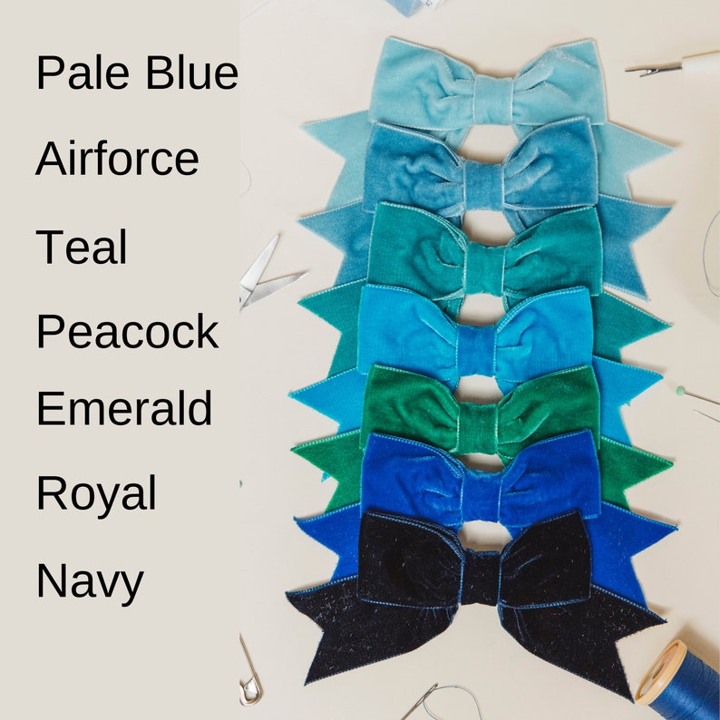 May include: Eight velvet bows in shades of blue and green, arranged in a row from lightest to darkest. The colors are labeled "Pale Blue", "Airforce", "Teal", "Peacock", "Emerald", "Royal", and "Navy".