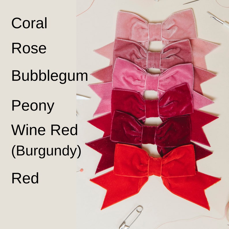 May include: Six velvet bows in shades of red, pink, and coral. The bows are arranged in a vertical stack, with the darkest red bow at the bottom and the lightest coral bow at the top. The bows are labeled with their corresponding colors: Red, Wine Red (Burgundy), Peony, Bubblegum, Rose, and Coral.