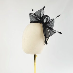 May include: A black mesh hair bow with a large, layered bow and a small, delicate bow. The bow is attached to a white mannequin head.