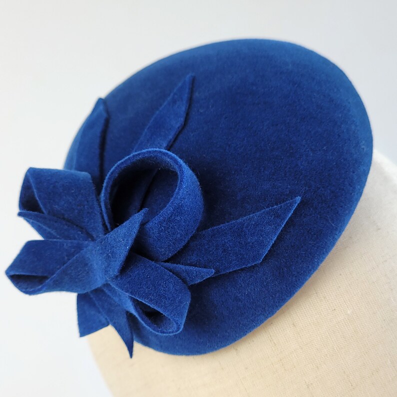 May include: A blue felt hat with a large blue felt bow on top.