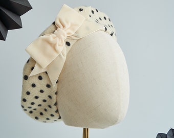 May include: A cream-colored beret with black polka dots and a large cream-colored satin bow.
