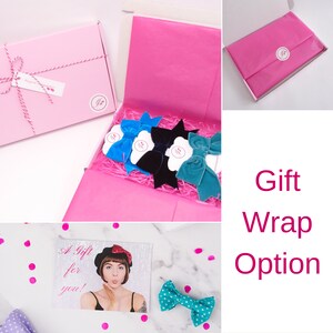 May include: A pink gift box with a white ribbon and a small tag that says "A Gift for you!"  The box is open and filled with pink tissue paper. Inside the box are four velvet hair bows in blue, black, and teal.