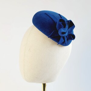 May include: A blue felt hat with a large felt bow on the side.