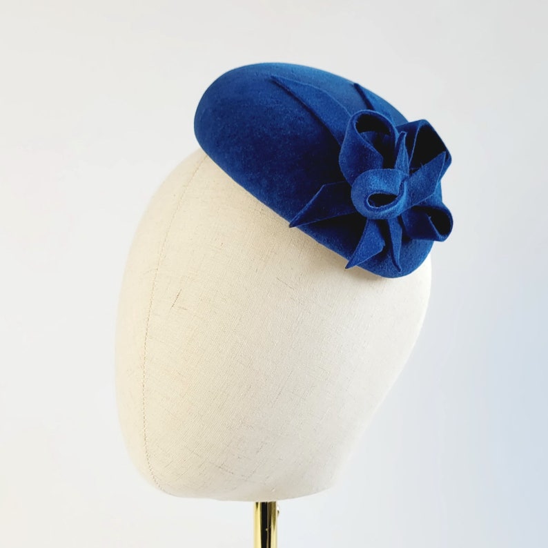 May include: A blue felt hat with a large felt bow on the side.