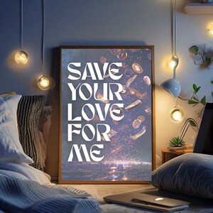 May include: A framed art print with the text "SAVE YOUR LOVE FOR ME" in white, with falling money and coins. The artwork is set in a bedroom with soft lighting and a laptop.