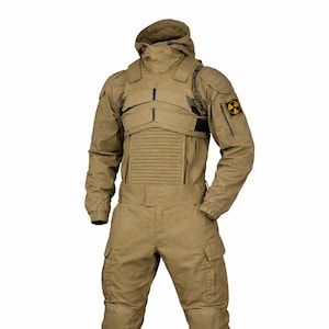 Op de afbeelding: Tan militair jumpsuit met een capuchon, borstbescherming en meerdere zakken. Het pak heeft een stralingsgevaarsymbool op de mouw en wordt gecombineerd met bijpassende gevechtslaarzen. Het ontwerp suggereert een tactisch of beschermend kledingstuk.