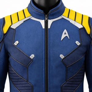 Puede incluir: Chaqueta azul de uniforme de la Flota Estelar con detalles amarillos en los hombros y ribetes plateados. La chaqueta presenta cierre de cremallera, insignia de la Flota Estelar y parche en el hombro. El dise&ntilde;o incluye detalles de malla y acolchado.