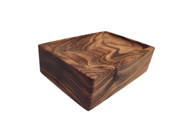 May include: A rectangular wooden tray with a carved interior. The tray is made of dark brown wood with a visible grain pattern. The sides are angled, and the interior has a shallow, contoured design. The tray is set against a white background.