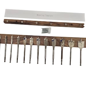 May include: A set of wood drill bits with a wooden holder and a mounting template. The drill bits are various sizes and are made of metal. The mounting template has the text "Mounting Template".