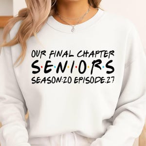 May include: A white crewneck sweatshirt featuring black text that reads OUR FINAL CHAPTER, SENIORS, and SEASON:20 EPISODE:27. The word SENIORS includes small, colorful dots between the letters, mimicking a well-known television show logo style.