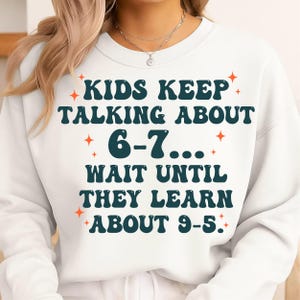 May include: White sweatshirt with the text "KIDS KEEP TALKING ABOUT 6-7... WAIT UNTIL THEY LEARN ABOUT 9-5." in teal and orange. The sweatshirt has a crew neck and long sleeves.