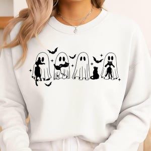 May include: A white crewneck sweatshirt featuring a black graphic print of four ghosts and several black cats. The design includes small star and bat silhouettes interspersed among the ghosts, creating a repeating pattern across the chest area.