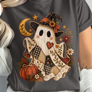 Könnte beinhalten: Ein dunkelgraues T-Shirt mit einer Grafik eines Geistes, der einen karierten Hexenhut trägt. Der Geist hat einen Körper im Patchwork-Stil mit Blumen- und Karomustern, ein rotes Herz, eine Mondsichel, einen Kürbis und verschiedene Herbstblumen.