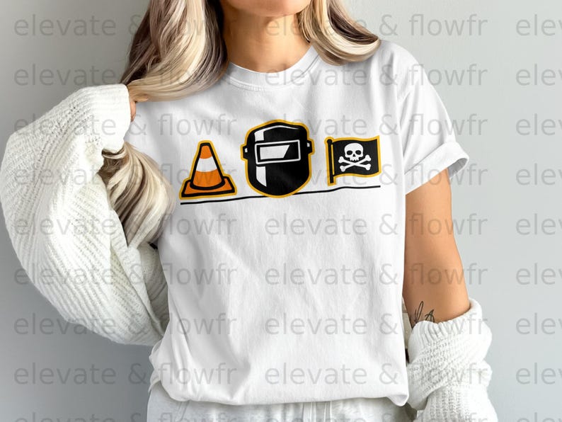 White t-shirt with a black graphic of a traffic cone, welding mask, and pirate flag.