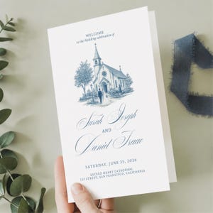 Könnte beinhalten: Ein weißes Hochzeitsprogramm mit einer blauen Tuschezeichnung einer Kirche und einem Paar davor. Der Text lautet: Welcome to the Wedding celebration of Sarah Joseph and Daniel Isaac, Saturday, June 25, 2026, Sacred Heart Cathedral.