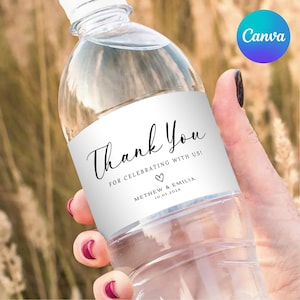 Könnte beinhalten: Eine transparente Plastikwasserflasche mit einem weißen Etikett. Das Etikett trägt den Schriftzug "Thank You" in Schreibschrift, gefolgt von "FOR CELEBRATING WITH US!" und einem Herzsymbol. Darunter steht "METHEW & EMILIA 10.05.2024".