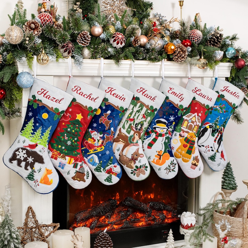 May include: Seven personalized Christmas stockings hanging in a row, each featuring unique embroidered holiday scenes including a bear, a tree, Santa, deer, a snowman, a gingerbread house, and penguins, with names Hazel, Rachel, Kevin, Hank, Emily, Laura, and Justin.