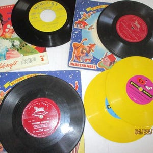 May include: A collection of vintage children's records with colorful covers and labels. The records are black, yellow, and red. The covers feature illustrations of rocking horses, farm animals, and a man in a hat. The text on the covers includes "Childcraft", "Mercury", "Rocking Horse", "Unbreakable", and "Golden Records".