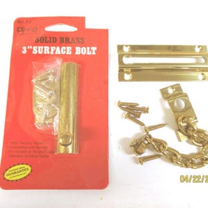 May include: A solid brass 3-inch surface bolt set with screws, a chain, and a strike plate. The set is packaged on a red card with the text "SOLID BRASS 3" SURFACE BOLT". Includes a guarantee seal.