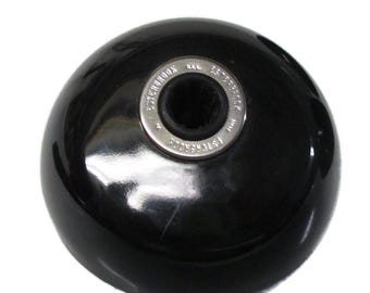 May include: A glossy black, dome-shaped Esterbrook inkwell base featuring a central circular metal collar. The silver-toned metal ring is embossed with the text Esterbrook repeated around the perimeter, surrounding a black, ribbed interior opening.