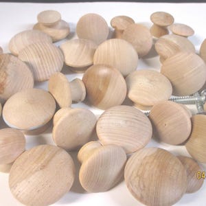 Może przedstawiać: Zbiór 25 nieoszlifowanych drewnianych gałek, idealnych do dodania rustykalnego charakteru meblom lub szafkom. Gałki są okrągłe i mają gładkie, naturalne wykończenie.