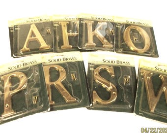 May include: A collection of solid brass letters, including A, H, K, O, P, R, S, and W, each packaged individually. The packaging reads "SOLID BRASS". Each letter is accompanied by mounting screws.