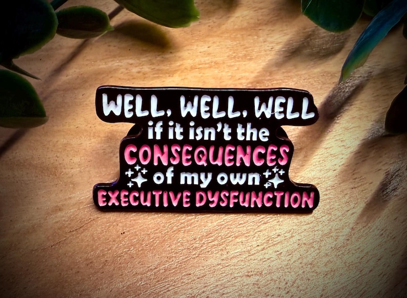 Puede incluir: Un pin de esmalte negro y rosa con el texto "WELL, WELL, WELL if it isn't the CONSEQUENCES of my own EXECUTIVE DYSFUNCTION". El pin tiene un borde blanco y acentos de estrellas.