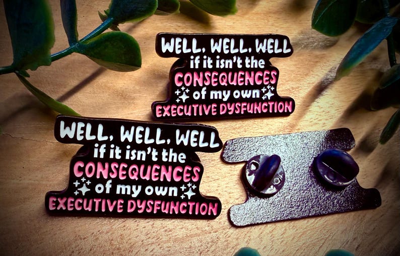 Puede incluir: Tres pines de esmalte negro con el texto "WELL, WELL, WELL if it isn't the CONSEQUENCES of my own EXECUTIVE DYSFUNCTION" en blanco y rosa. Los pines tienen un cierre de mariposa.