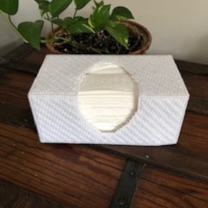 May include: White tissue box cover with a woven pattern and an oval opening for dispensing tissues.