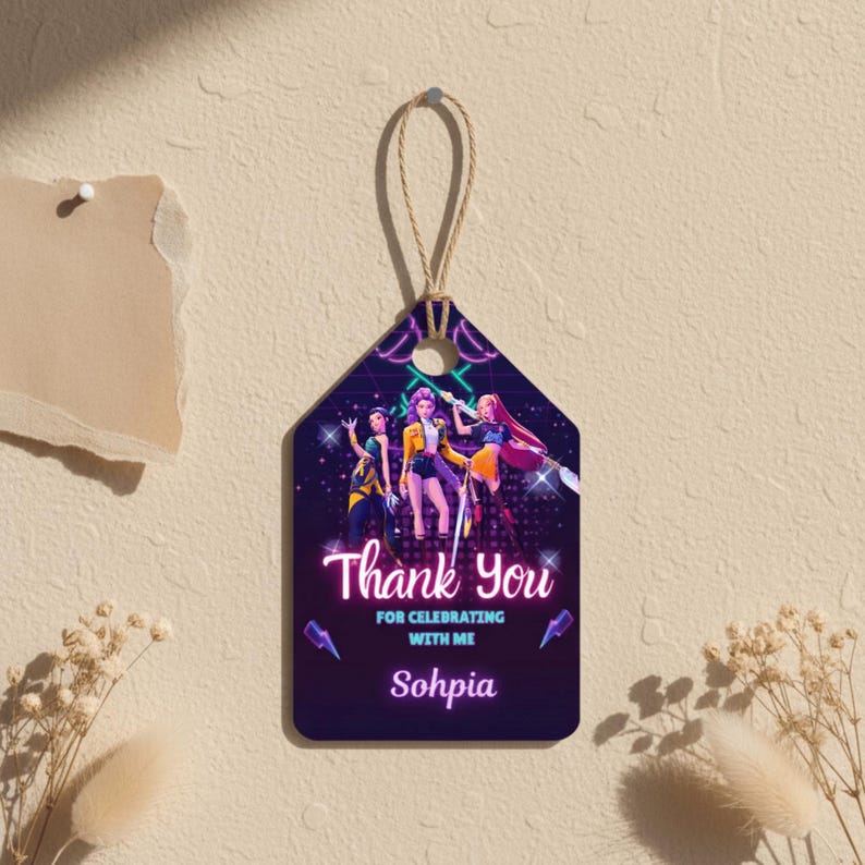 May include: A hanging tag with a string, featuring a graphic of three women in vibrant outfits. The tag displays the words "Thank You" and "For Celebrating With Me" in a neon font, with the name "Sohpia" below the text.