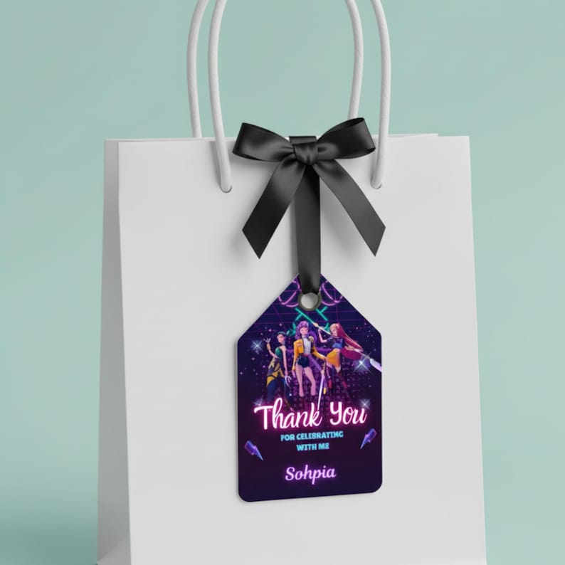 May include: A white gift bag with a black bow and a tag. The tag features a dark purple background with a group of people and the words "Thank You" and "For Celebrating With Me" and the name "Sohpia".