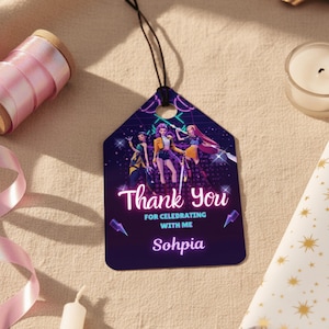 May include: A dark purple gift tag with a black string, featuring a graphic of three women and the text "Thank You for Celebrating with Me Sohphia". The tag has a geometric shape with a hole at the top.