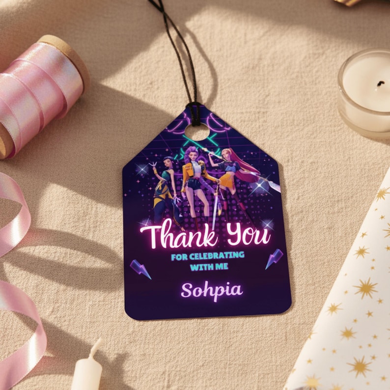 May include: A dark purple gift tag with a black string, featuring a graphic of three women and the text "Thank You for Celebrating with Me Sohphia". The tag has a geometric shape with a hole at the top.