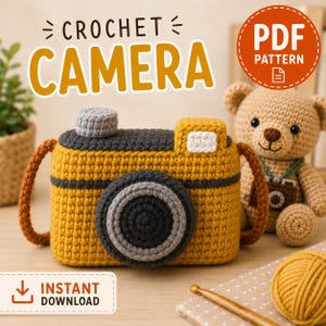 Op de afbeelding: Een haakpatroon PDF van een camera gemaakt van mosterdgeel en donkergrijs garen met een lichtgrijze lens en bovenste knop. De tekst CROCHET CAMERA en PDF PATTERN is zichtbaar. Een gehaakte bruine teddybeer staat naast de camera.