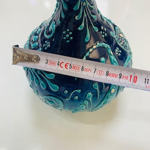 Könnte beinhalten: Eine dunkelblaue Keramikvase mit türkisfarbenen Akzenten und verzierten floralen Mustern. Die Vase hat einen Durchmesser von ca. 10 cm, gemessen mit einem Maßband. Die Vase hat eine glänzende Oberfläche und eine bauchige Form.